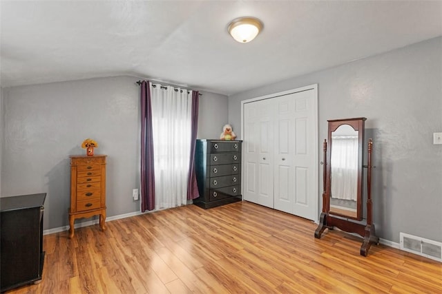 bedroom featuring vaulted ceiling, light hardwood / wood-style floors, and a closet