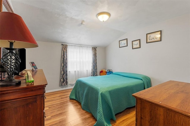 bedroom with vaulted ceiling and light wood-type flooring