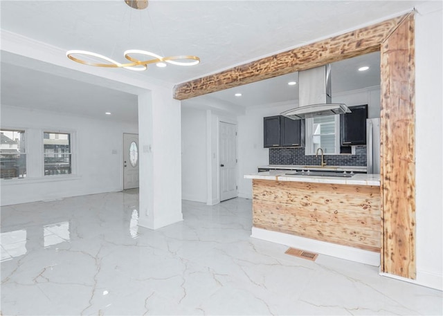 kitchen with sink, tasteful backsplash, ornamental molding, pendant lighting, and island exhaust hood