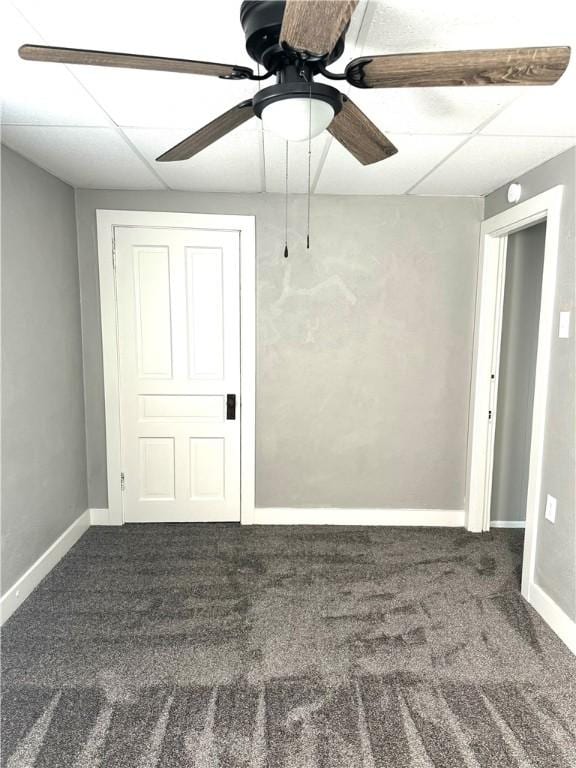 carpeted spare room featuring ceiling fan and a drop ceiling