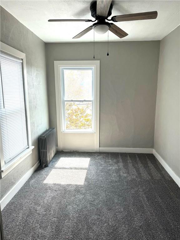 carpeted spare room with radiator heating unit and a textured ceiling