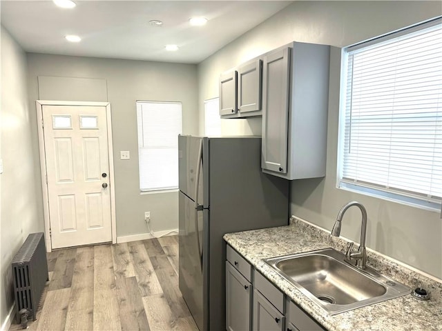 kitchen featuring sink, radiator heating unit, light hardwood / wood-style floors, and gray cabinetry