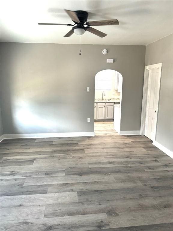 unfurnished room with sink, ceiling fan, and light wood-type flooring