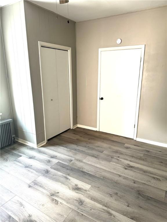 unfurnished bedroom with radiator heating unit, light wood-type flooring, and a closet