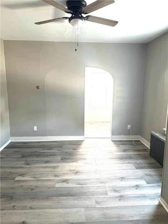 spare room featuring hardwood / wood-style flooring, radiator heating unit, and ceiling fan