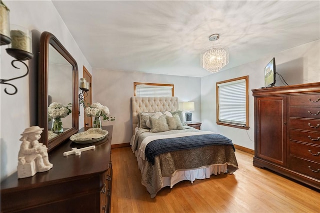 bedroom featuring an inviting chandelier and light wood-type flooring