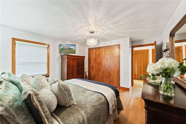 bedroom featuring an inviting chandelier, light hardwood / wood-style floors, and a closet