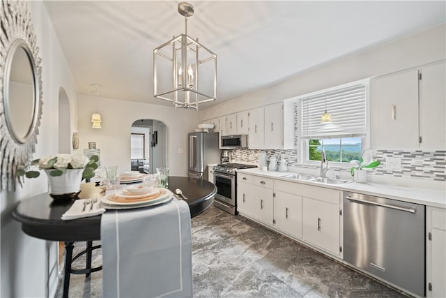 kitchen featuring white cabinetry, appliances with stainless steel finishes, decorative light fixtures, and sink