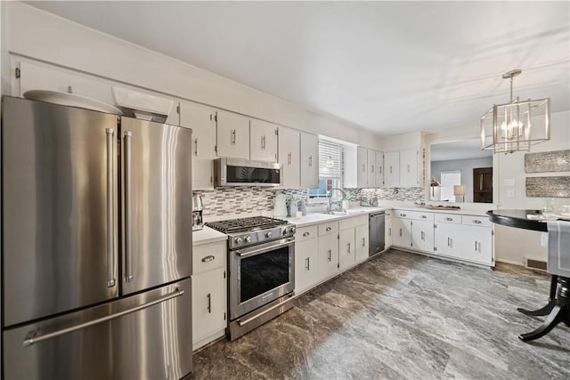 kitchen with sink, white cabinets, premium appliances, and decorative light fixtures