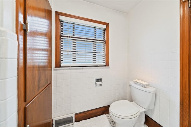 bathroom with tile walls and toilet