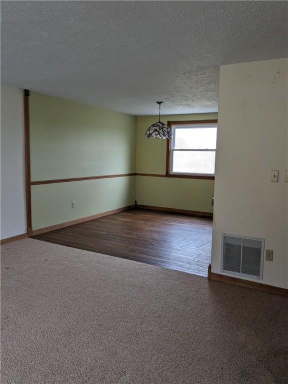 carpeted empty room featuring a textured ceiling