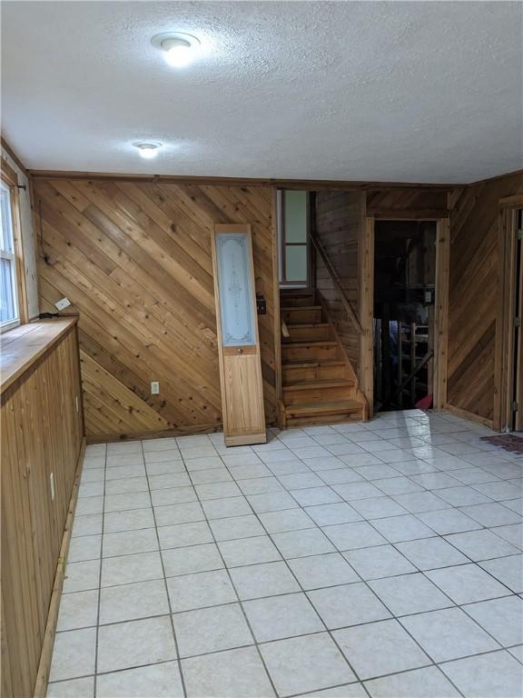 unfurnished room with a textured ceiling and wood walls