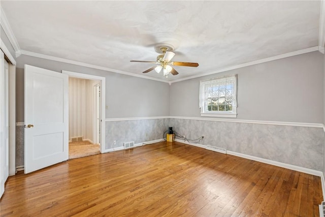 spare room with crown molding, wood-type flooring, and ceiling fan