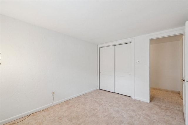 unfurnished bedroom featuring light colored carpet and a closet