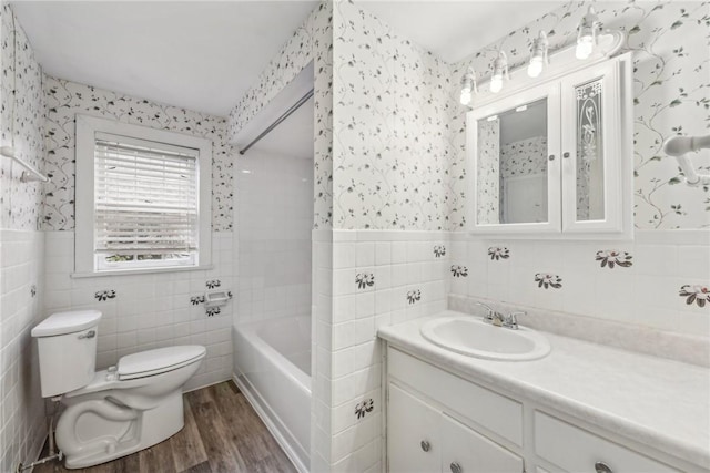 bathroom with tile walls, vanity, wood-type flooring, a tub to relax in, and toilet