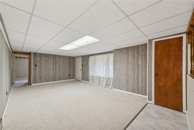 basement with a drop ceiling and wood walls