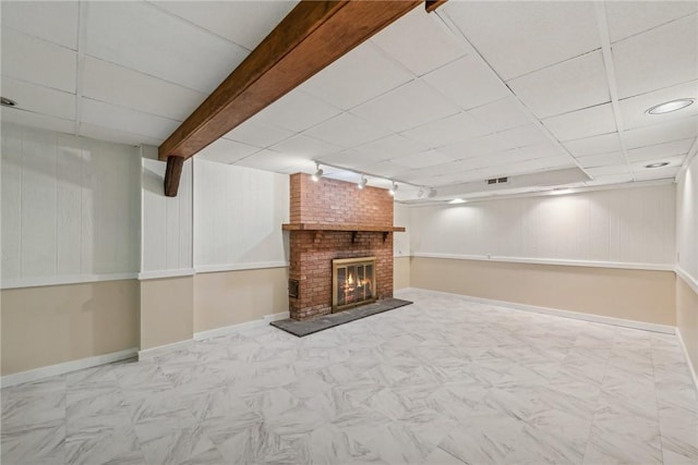 basement with a brick fireplace, track lighting, and a paneled ceiling