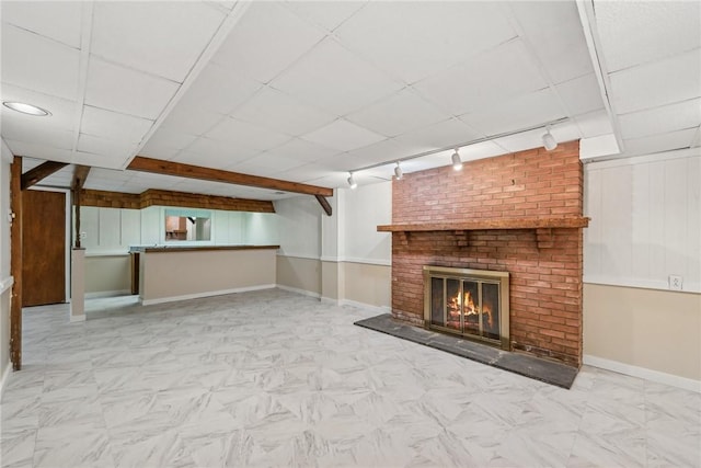 unfurnished living room featuring track lighting and a brick fireplace