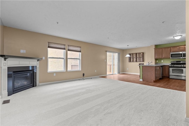 kitchen with appliances with stainless steel finishes, carpet floors, and pendant lighting