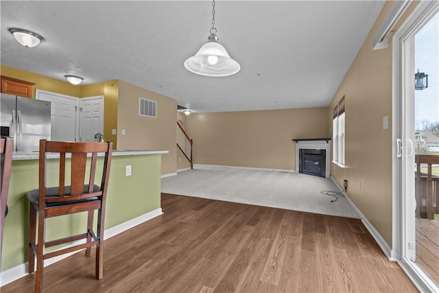 kitchen with hardwood / wood-style floors, stainless steel fridge, and decorative light fixtures