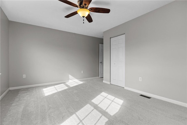 unfurnished bedroom featuring ceiling fan, a closet, and light carpet