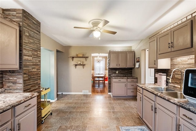 kitchen with ceiling fan with notable chandelier, sink, and decorative backsplash