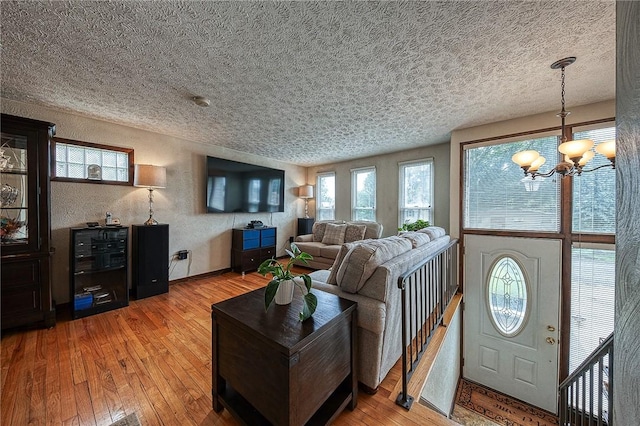 living room featuring an inviting chandelier, light hardwood / wood-style floors, and a textured ceiling