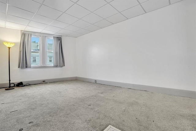 carpeted empty room featuring a paneled ceiling