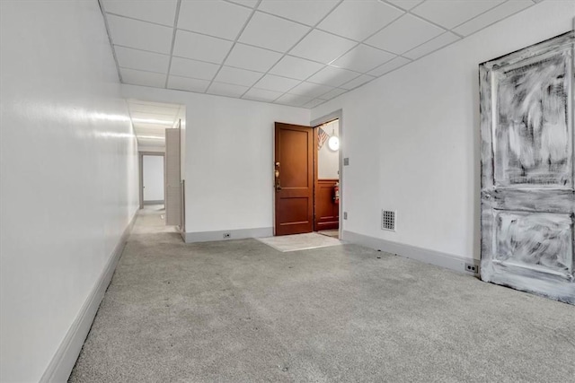 empty room featuring a paneled ceiling and light colored carpet