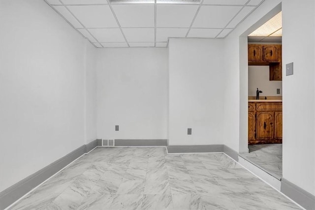 unfurnished room featuring sink and a paneled ceiling