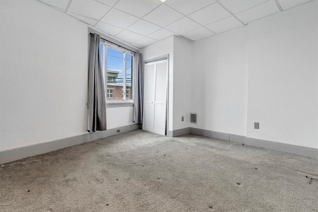 empty room featuring a paneled ceiling and light carpet