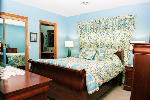 bedroom with ensuite bathroom, light colored carpet, and a closet