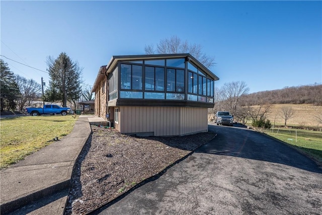 view of home's exterior featuring a sunroom and a lawn