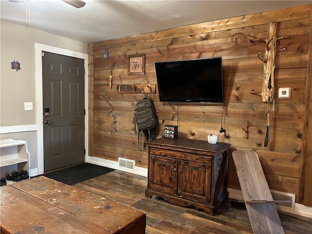 interior space with dark wood-type flooring and wooden walls