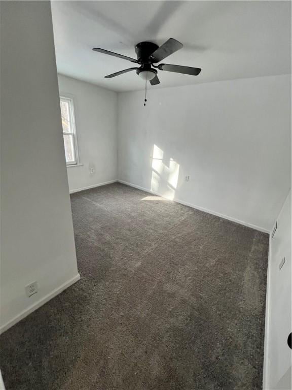 unfurnished room with dark carpet, baseboards, and ceiling fan