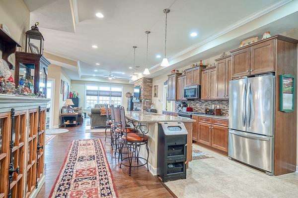 kitchen with appliances with stainless steel finishes, an island with sink, a kitchen bar, decorative light fixtures, and a raised ceiling