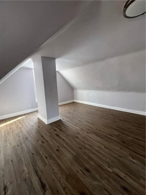 bonus room featuring dark wood-type flooring and vaulted ceiling