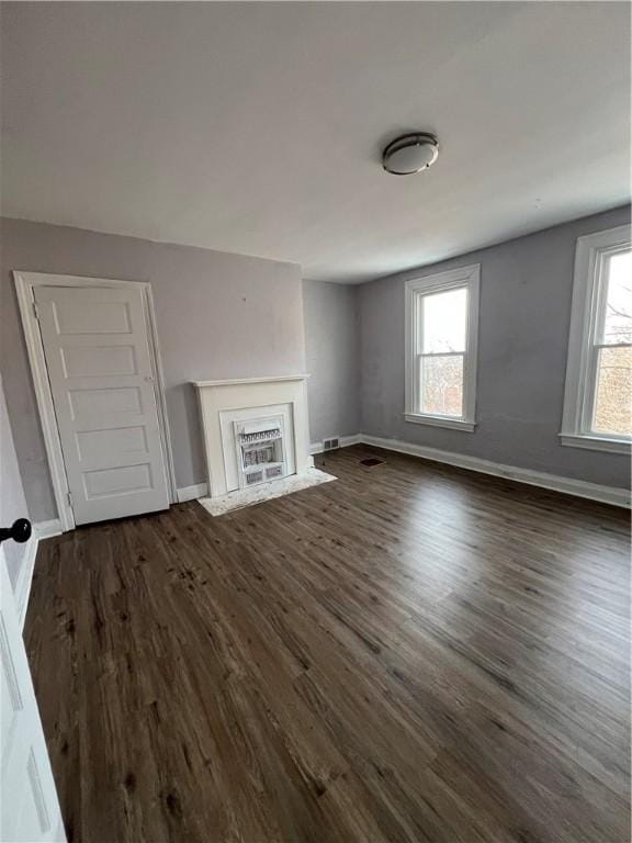 unfurnished living room featuring dark wood-type flooring and a wealth of natural light