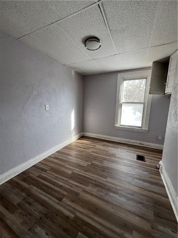 spare room with dark wood-type flooring and a paneled ceiling