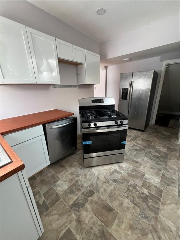 kitchen with wood counters, white cabinets, and appliances with stainless steel finishes