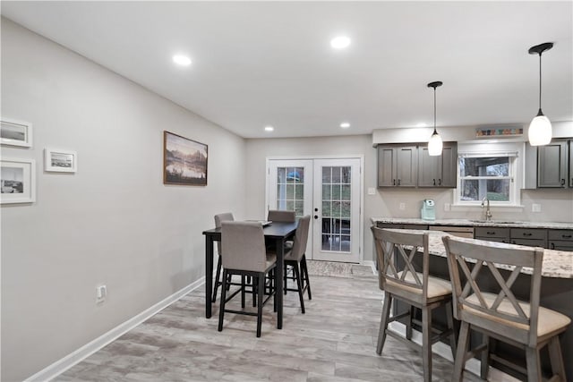 dining room with sink, a wealth of natural light, french doors, and light wood-type flooring