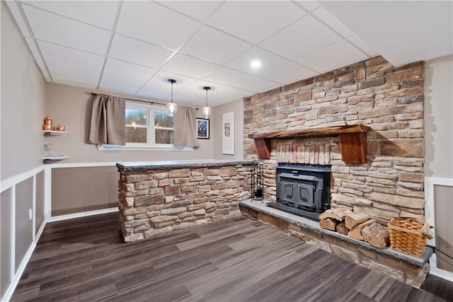 interior space with dark hardwood / wood-style flooring, a paneled ceiling, and a wood stove