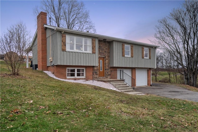 bi-level home featuring a garage and a yard