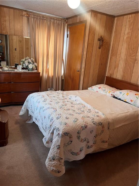 bedroom with carpet floors and wooden walls