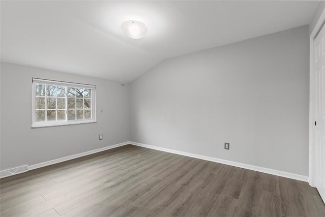 additional living space featuring vaulted ceiling and dark wood-type flooring