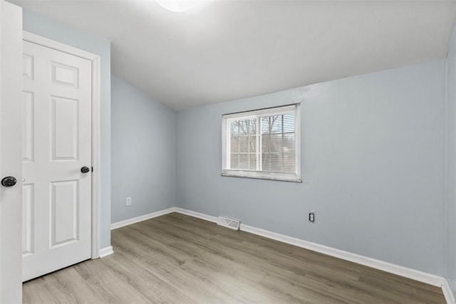 empty room with lofted ceiling and light wood-type flooring