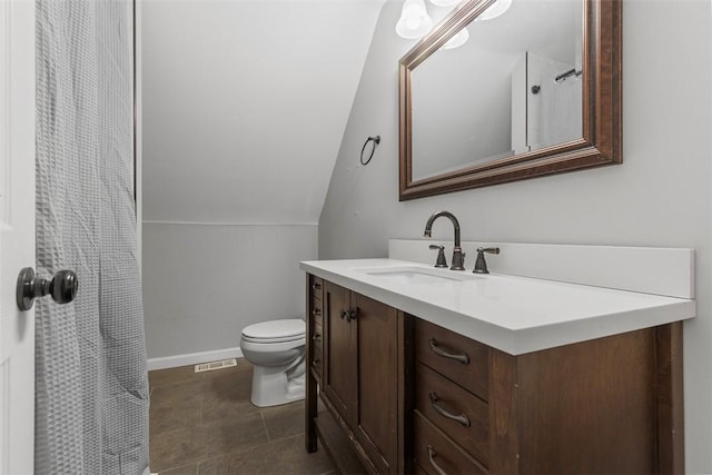 bathroom featuring vanity, toilet, and vaulted ceiling