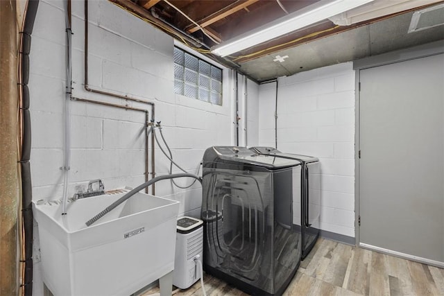 laundry room featuring sink, washer and clothes dryer, and light hardwood / wood-style floors