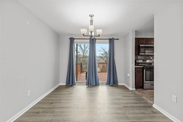 unfurnished dining area with an inviting chandelier and light wood-type flooring