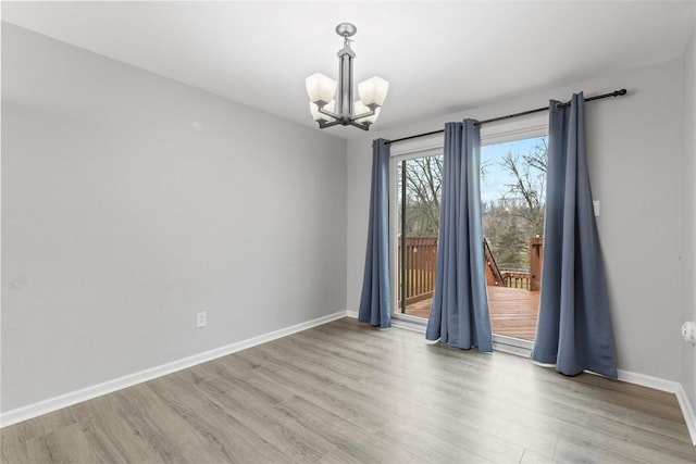 empty room with a chandelier and light hardwood / wood-style floors